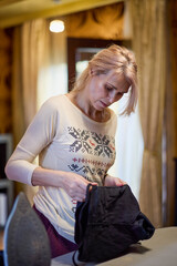 portrait of a woman ironing clothes with an ironing station at home. blurred background.