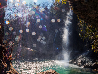 Beautiful waterfall in the jungle. Water quickly flows into a mountain lake. Splashes in the foreground. Sunny weather. Horizontal. No people