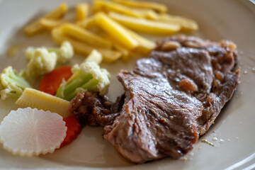 Medium rare meat steak on plate with french fries