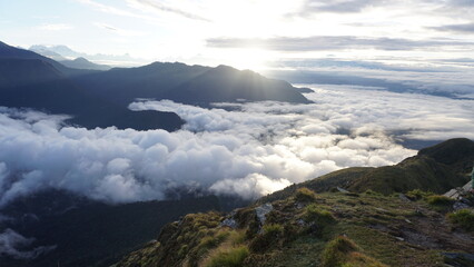 view from an observation hill on top of a mountain with clouds covering the landscape