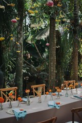 Arrangement decoration for intimate gathering with families or friends. Indonesian culture. Balinese, Javanese. Flower drops and hanging ornaments. Table setting. Long dinner table