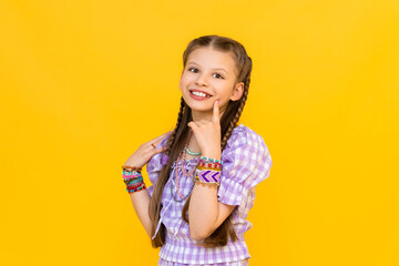 The child put on a lot of bracelets made of beads and beads. A happy little girl is enjoying a...