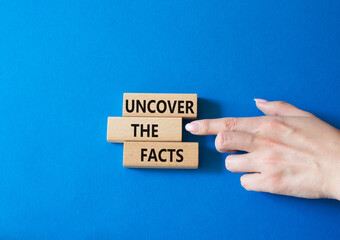 Uncover the Facts symbol. Concept word Uncover the Facts on wooden blocks. Businessman hand. Beautiful blue background. Business and Uncover the Facts concept. Copy space