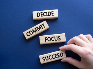 Decide Commit Focus Succeed symbol. Concept words Decide Commit Focus Succeed on wooden blocks. Businessman hand. Beautiful deep blue background. Business concept. Copy space.