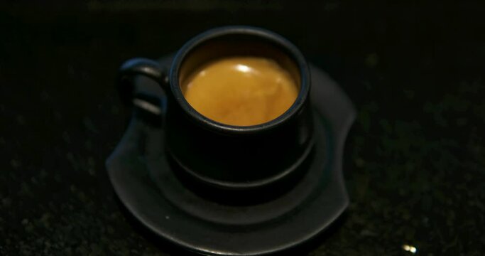 Hearts embedded in frothy cappuccino in black mug on mahogany table parallax black coffee cup