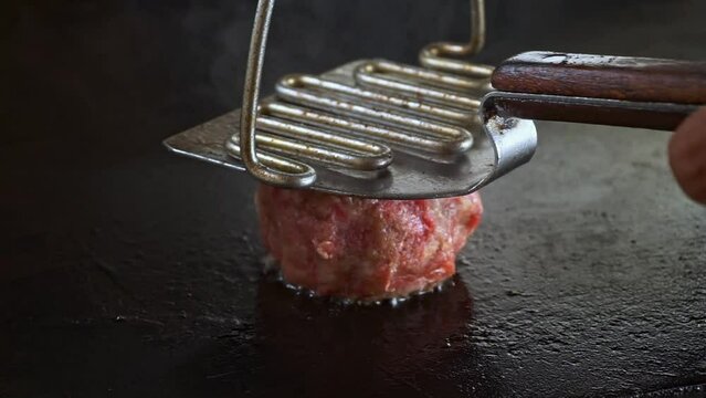 smashing hamburger patty in a flat griddle, smashing or pressing meat patty, smash burger