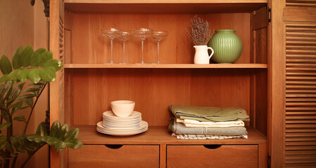 Fototapeta na wymiar Retro styled cupboard with disheslike plates, tableclothes, vases and glasses