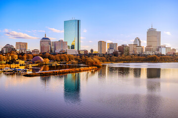 Fototapeta na wymiar Boston City Skyline over the Charles River in Massachusetts, USA. A tranquil riverscape of Back Bay with golden illuminated wintery foliage in New England.
