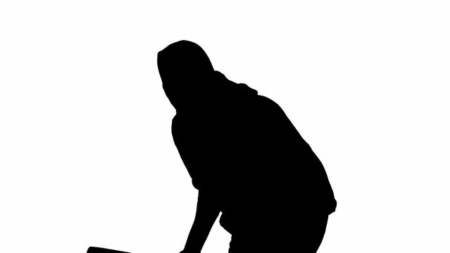 Black silhouette of thief on isolated white background. A male robber in hoodie and balaclava walks with a wooden club in his hands, preparing to commit a crime. Half-turn.