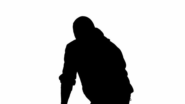 Black silhouette of thief on isolated white background. Male robber in hoodie and balaclava walking with a gun in his hands, preparing to commit a crime. Half-turn.