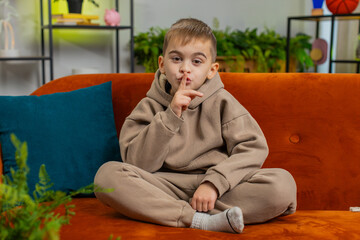 Shh be quiet please. Preteen child boy presses index finger to lips makes silence hush gesture sign...
