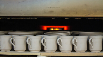 rows of white identical mugs visited in a muffle kiln at a porcelain factory in Likino-Dulevo in the Moscow region