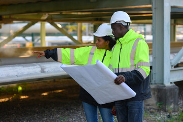 Male and female engineers check the drawing system inspection with the real pipe system of the new...