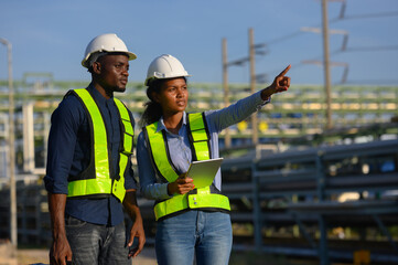 Male and female engineers check the drawing system inspection with the real pipe system of the new...