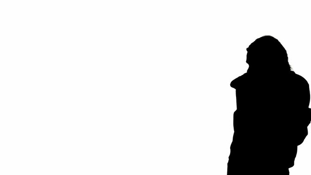Black silhouette of a woman on a white isolated background. A young girl walks, looking around frightened, fleeing faster from danger. Side view.