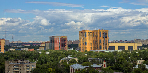 A residential area with modern multi-storey buildings among green trees in Reutov, Moscow region on a sunny summer day and a space for copying