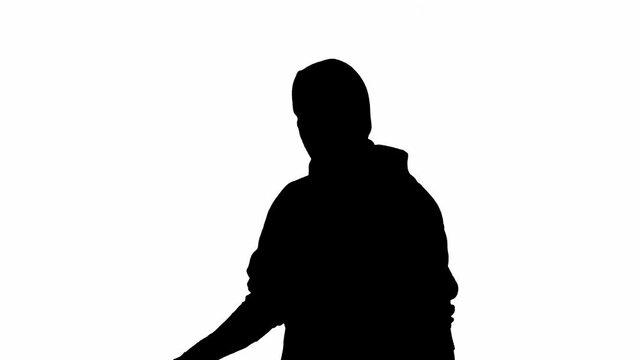 Black silhouette of thief on isolated white background. Male robber in hoodie and balaclava walking, preparing to commit a crime. Half-turn.