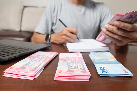 Close up of man's hands counting Indonesian rupiah notes and making notes, money financial management concept. Soft focus, Selective focus