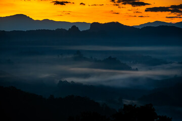 Silhouettes of mountains visible through colorful mist in the morning
