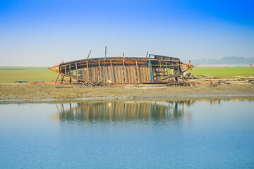 Repairing a wooden boat on the riverbank in Bangladesh.