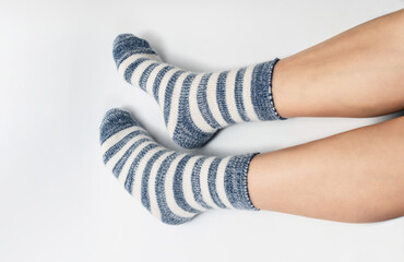 Side view of legs in socks of two colors alternating blue and white. White background, isolated.