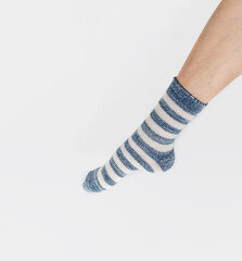 Warm fluffy striped socks on bare female feet. The concept of warmth and rest.
