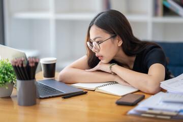 Freelance Asian businessperson, Business woman sitting collapsed on the arm and thinking about work. Staring at the laptop screen while thinking analytically.