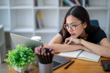 Freelance Asian businessperson, Business woman sitting collapsed on the arm and thinking about work. Staring at the laptop screen while thinking analytically.