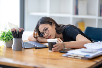 Freelance Asian businessperson, A businesswoman sits slumped on arm at her desk in a bored mood....