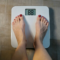 Kobieta stojąca na wadze. Na wyświetlaczu widoczna waga kobiety. Kontrola wagi, odchudzanie - obrazy, fototapety, plakaty