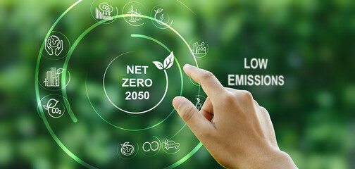 Hand points to a touchscreen with the word Net Zero and an icon against a green background. Concept, goal, zero greenhouse gas emissions. and a long-term climate-neutral strategy. - obrazy, fototapety, plakaty