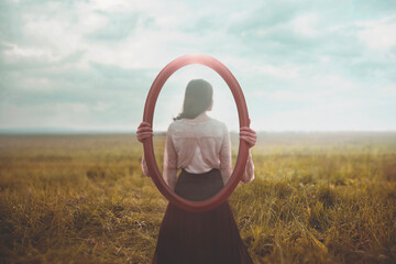 woman holding a mirror who is mirrored appears from behind, identity concept - obrazy, fototapety, plakaty