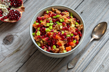 Homemade kisir - spicy Turkish bulgur wheat salad in a bowl, half a pomegranate, and a spoon, next...