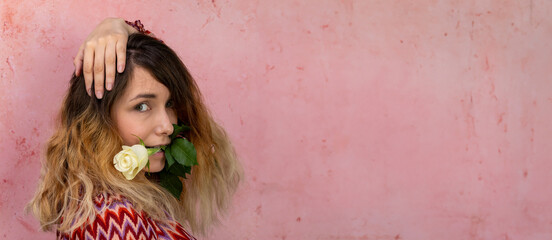 Woman with white rose in her teeth at pink textured background. Banner with copy space for text.