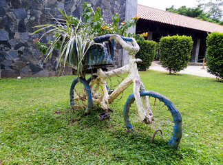 Fototapeta premium a bike planter is sitting in the grass by a building, Srilanka