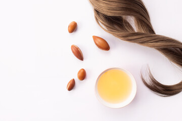 Hairloss concept. Argan seeds, oil and hair isolated on a white background - obrazy, fototapety, plakaty