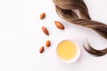 Fotobehang Hairloss concept. Argan seeds, oil and hair isolated on a white background © Oksana