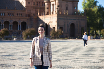 Young and beautiful woman in casual clothes is visiting the famous Plaza de Espana in Seville. The woman enjoys travelling around the old european city. Holiday and travel concept.