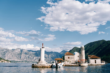 Boats are moored near the small island of Gospa od Skrpjela in the Bay of Kotor. Montenegro - obrazy, fototapety, plakaty