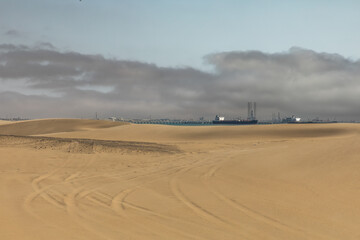 Fototapeta na wymiar The port of Walvis Bay is seen beyond the sand dunes of the Namib desert.