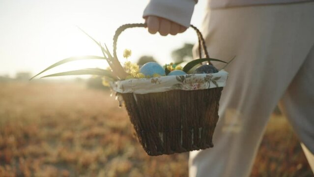 Woman in White Strolls with a Basket of Easter Eggs under the Morning Sunbeams in the Forest. Close-Up, Slow Motion.
