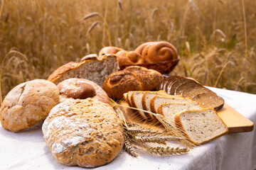 Lot of different flavored bread, wheat, rye, on the table in the field outside