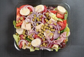 salad complete with lettuce, tomatoes, onions and peas seen from above in packaging for delivery