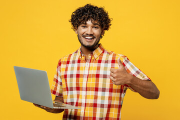Young smiling happy programmer IT Indian man wears shirt casual clothes hold use work on laptop pc...