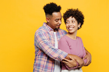 Young happy lovely couple two friend family man woman of African American ethnicity wear purple casual clothes together hug cuddle look to each other isolated on plain yellow orange background studio