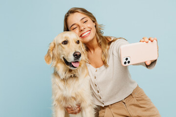 Young fun owner woman with her best friend retriever wear casual clothes do selfie shot on mobile cell phone hug dog isolated on plain pastel light blue background studio Take care about pet concept