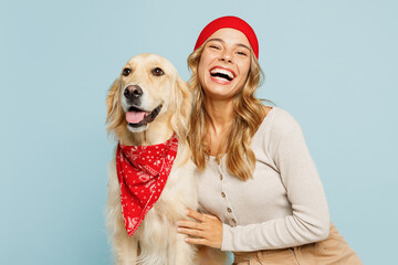 Young owner woman wear casual clothes red hat bandana looking camera hug cuddle embrace her best friend retriever dog isolated on plain pastel light blue background studio Take care about pet concept