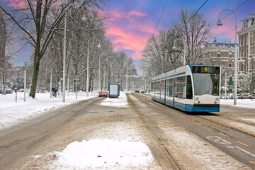 Obraz premium Tram driving in snowy Amsterdam in the Netherlands at sunset