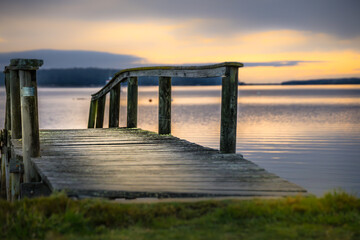 Wooden dock extends out into the tranquil lake at sunset