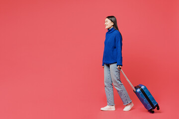 Side view traveler woman wear blue sweater casual clothes hold bag walk isolated on plain pastel pink background. Tourist travel abroad in free spare time rest getaway Air flight trip journey concept